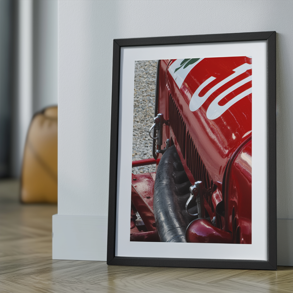 A framed photo showing the side of a vintage red race car with white numbering