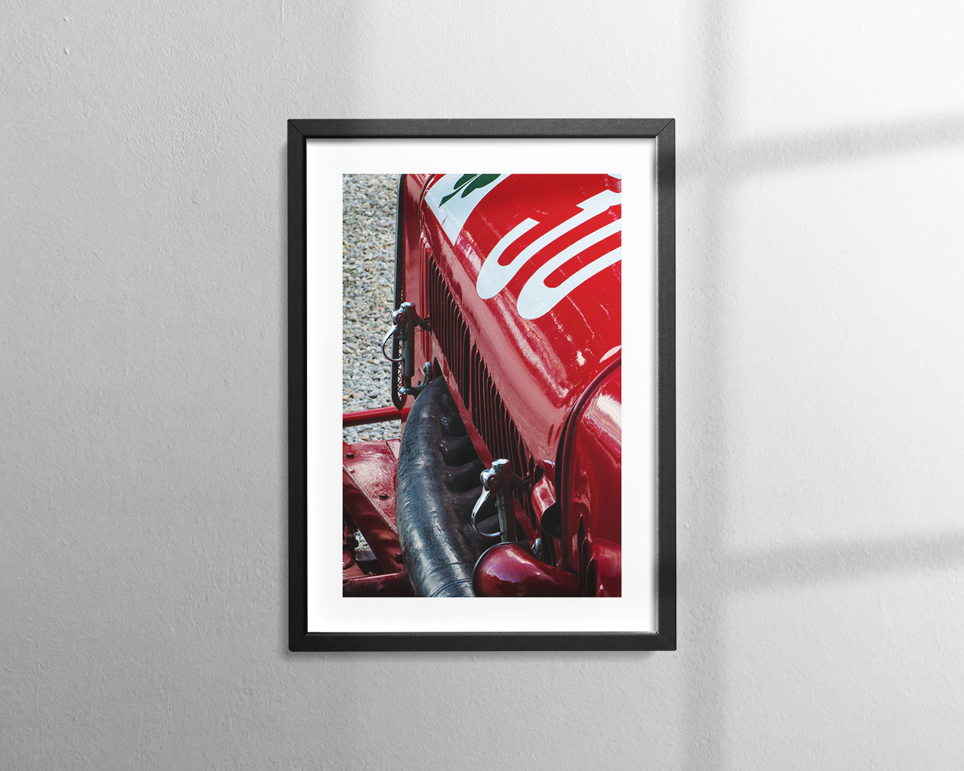 A close-up view of the red bodywork, grille, and white lettering on the hood of a vintage Alfa Romeo P2 race car