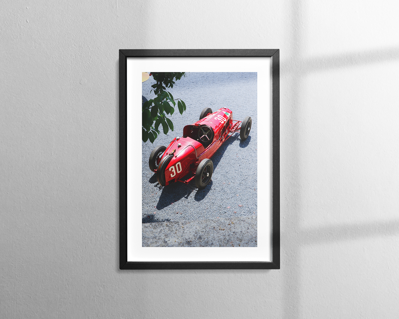 A vintage red Alfa Romeo P2 race car with the number 30 on its front is parked on an asphalt surface.