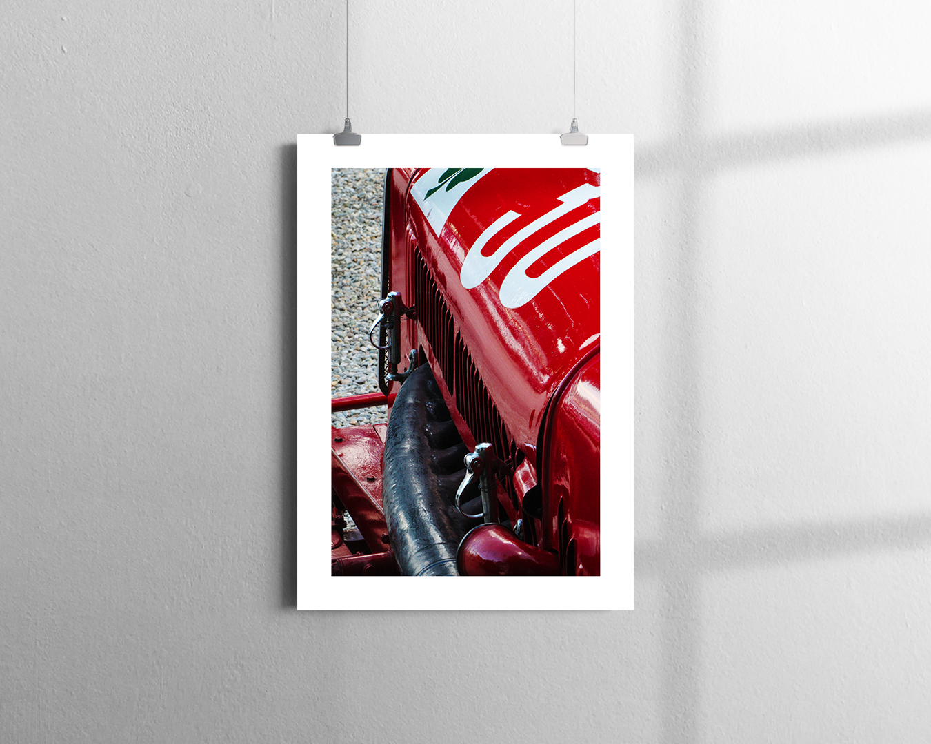 Close-up view of a vintage red racing car, possibly an Alfa Romeo, with white racing stripes on the hood